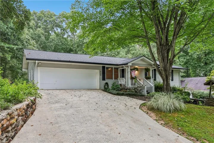 Ranch-style exterior with gray siding, a prominent two-car garage, and a covered front porch featuring white railings