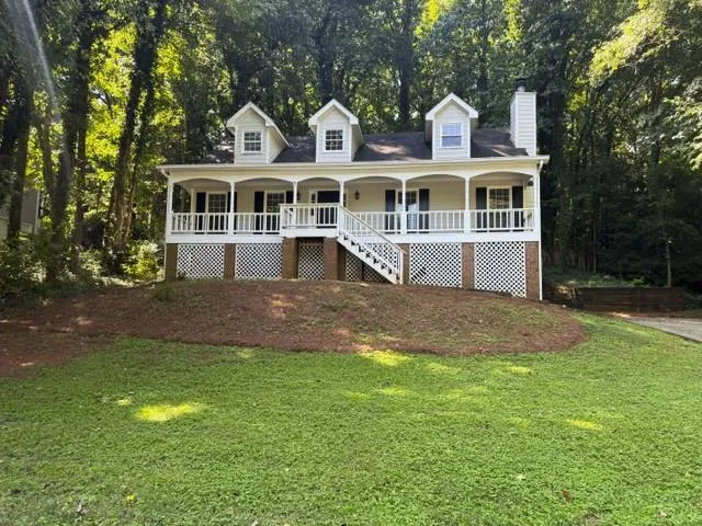 Traditional-style home featuring a covered front porch, white railing, three dormer windows, and a brick chimney