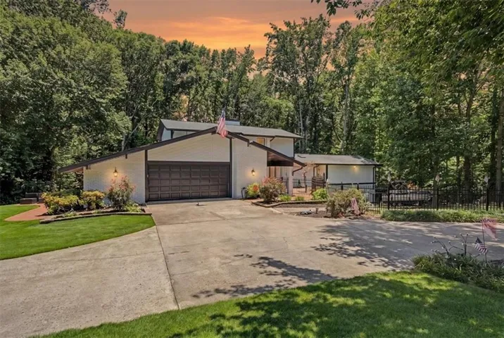 Contemporary residence featuring a two-car garage, concrete driveway, and white brick facade