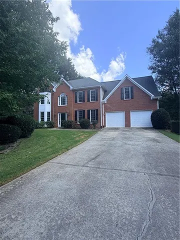 Brick exterior with a prominent arched window, dark shutters, and a two-car garage