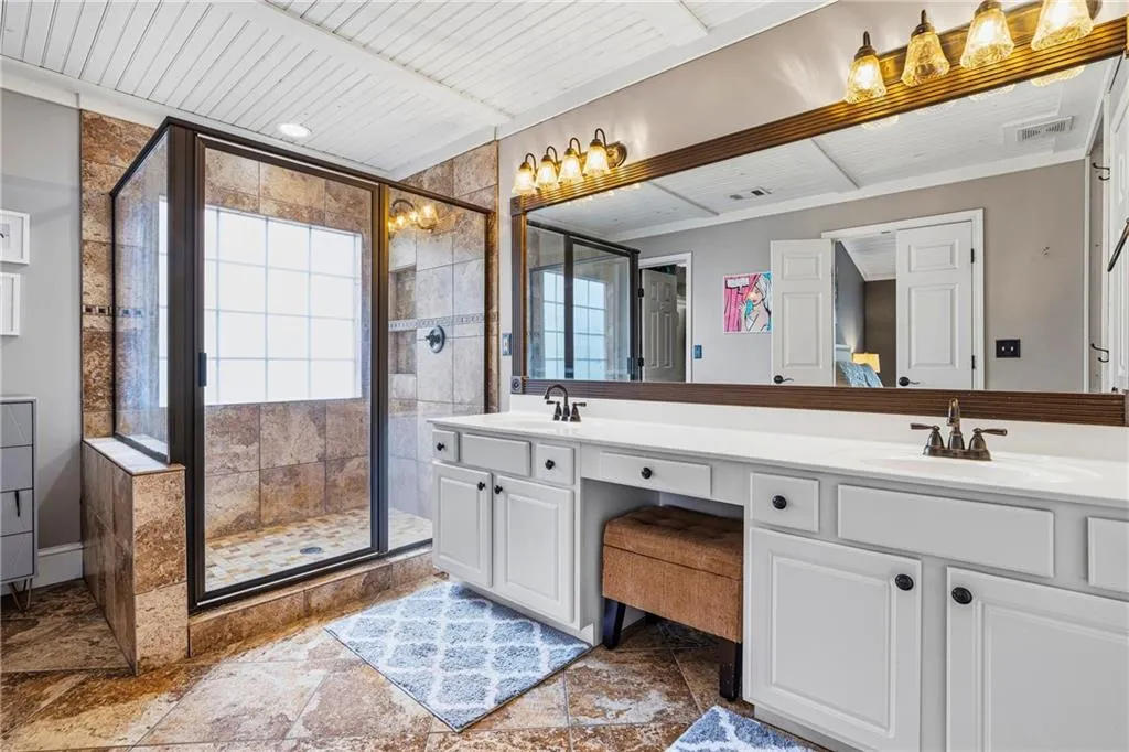 Expansive vanity with dual sinks, white cabinetry, and a large mirror