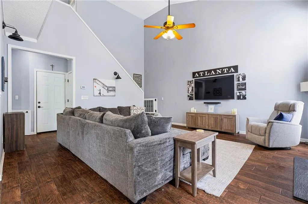 Vaulted ceiling with a ceiling fan, dark wood-finish flooring, and a white paneled door