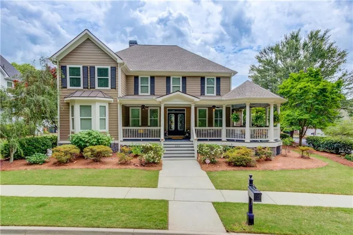 Traditional-style residence featuring a prominent covered front porch, an integrated gazebo, a bay window, and manicured landscaping