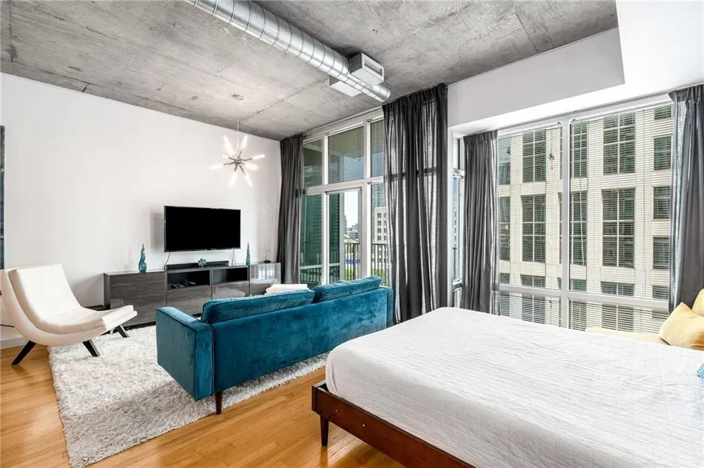 Bedroom with wood finished floors, a chandelier, and expansive windows