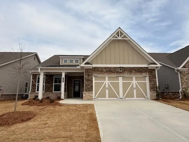 Craftsman-style home with driveway, an attached garage, covered porch, brick siding, and board and batten siding
