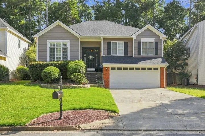 Two-story residence featuring light gray siding, brick accents, and a two-car garage
