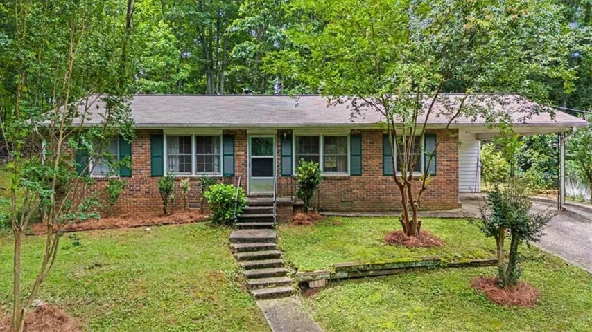 Brick exterior with green window shutters, a front porch, and a concrete walkway