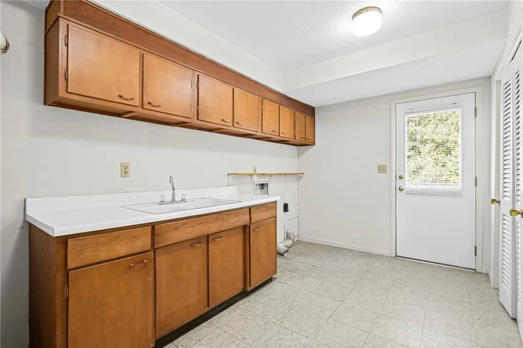 Laundry Room on lower level has a sink, solid wood cabinetry, laundry chute and exterior access