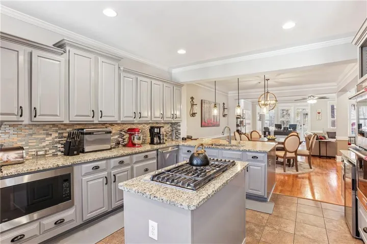 Kitchen with open floor plan, stainless steel appliances, a chandelier, decorative light fixtures, and a center island