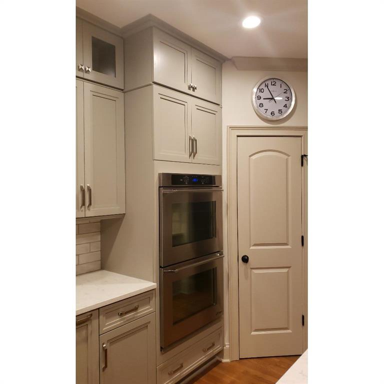 Kitchen featuring double oven, light hardwood / wood-style flooring, gray cabinetry, and light stone counters
