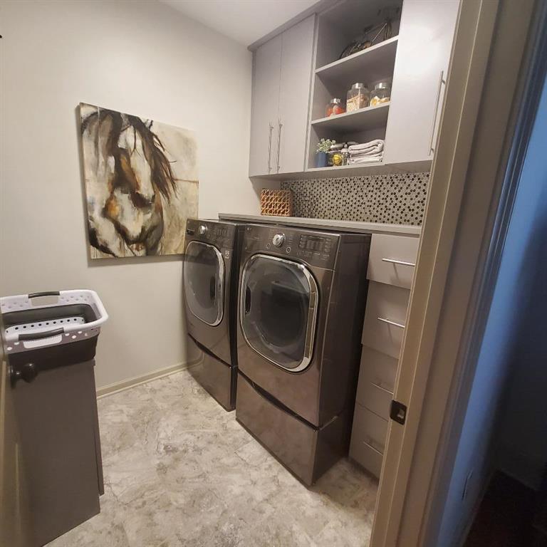 Washroom featuring light tile flooring, separate washer and dryer, and cabinets