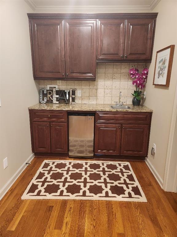 Bar featuring dishwasher, light stone countertops, dark hardwood / wood-style floors, and backsplash