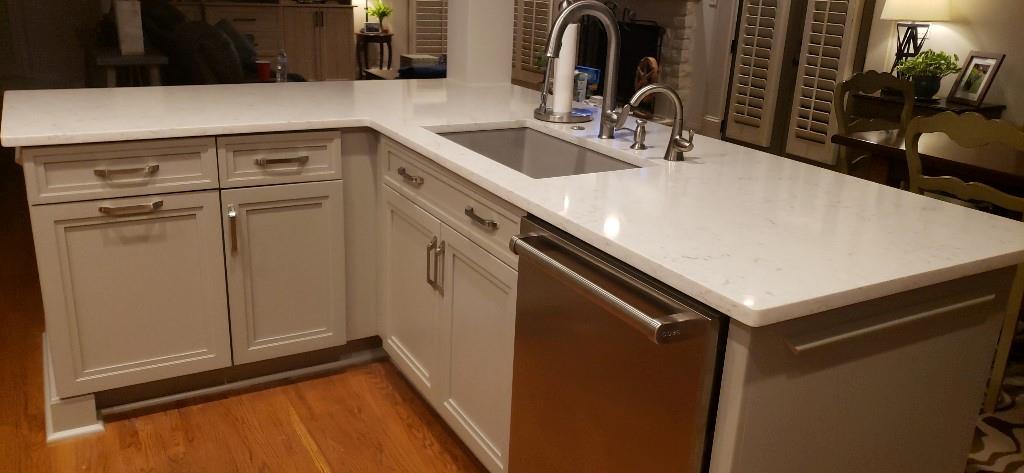 Kitchen featuring sink, light wood-type flooring, kitchen peninsula, and stainless steel dishwasher