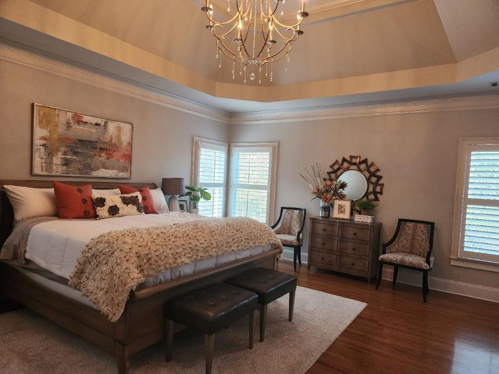 Bedroom with multiple windows, a notable chandelier, and a raised ceiling