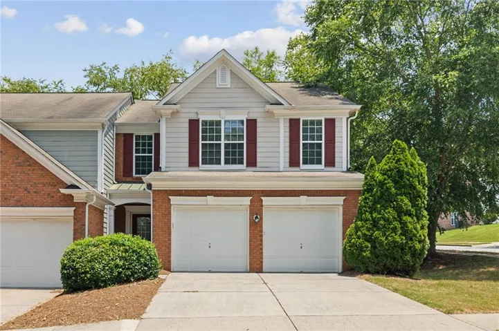 Two-story residence featuring a brick and siding facade, covered entry, and a two-car garage
