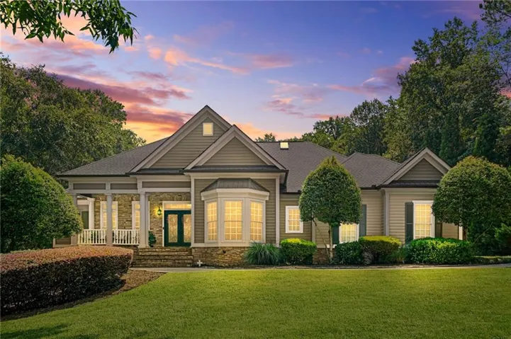 Expansive front lawn leading to a stone porch with white pillars and railing