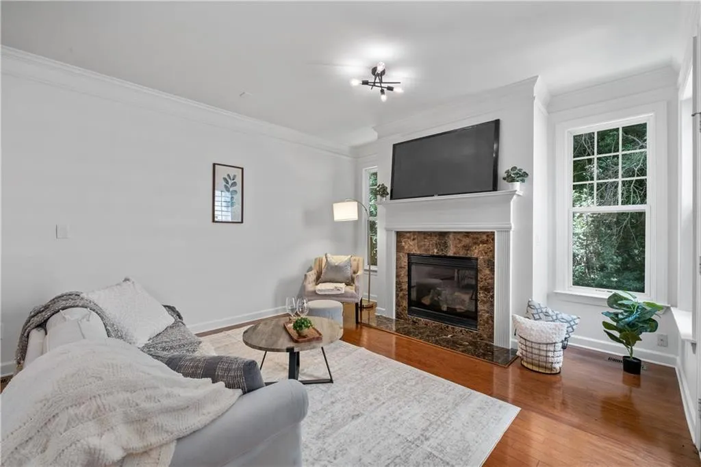 Living area with crown molding, wood finished floors, and a fireplace