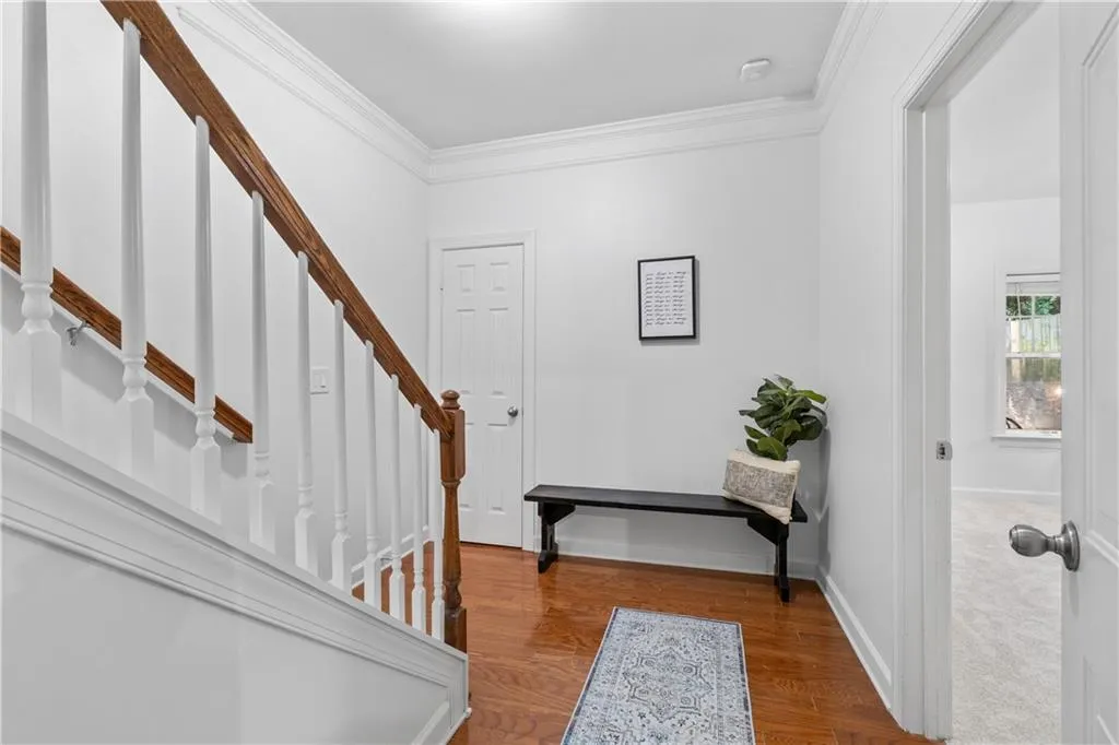 Entryway featuring ornamental molding, wood finished floors, and stairway