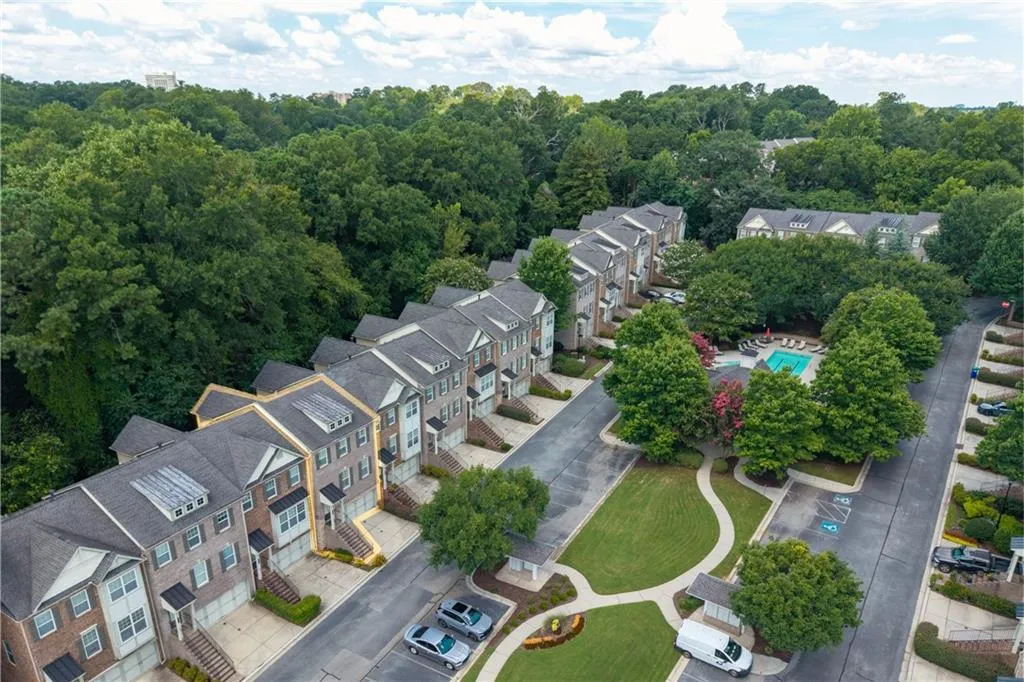 Aerial perspective of suburban area featuring a pool and a heavily wooded area