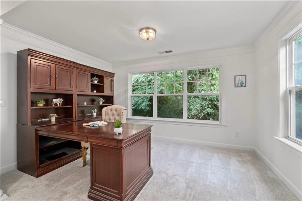 Office space with crown molding and light colored carpet