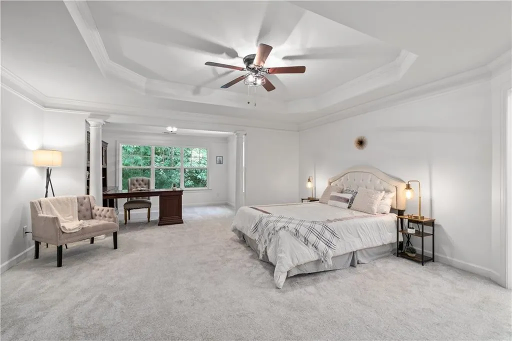 Bedroom featuring ornamental molding, carpet floors, a tray ceiling, and ornate columns
