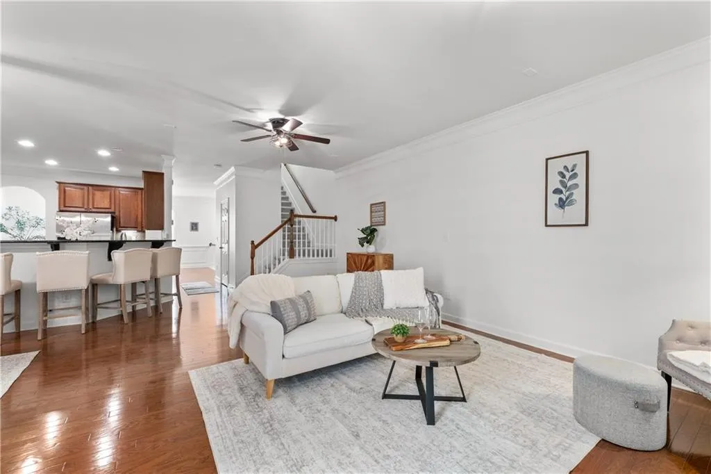 Living room featuring wood finished floors, ornamental molding, a ceiling fan, stairway, and recessed lighting
