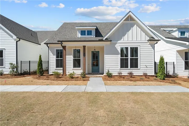 White board and batten and horizontal siding exterior, covered entry with wood-wrapped columns, dormer window, gray shingle roof, and concrete pathway