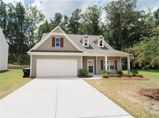 Single-story residence featuring a covered front porch, attached garage, and dormer windows