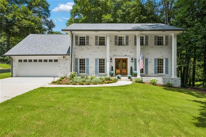 Colonial-style residence updated with white painted brick facade and a multi-level roofline