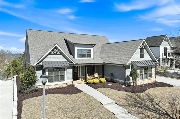 Craftsman-style exterior featuring light gray siding, stone accents, and dark gray shingle roofing