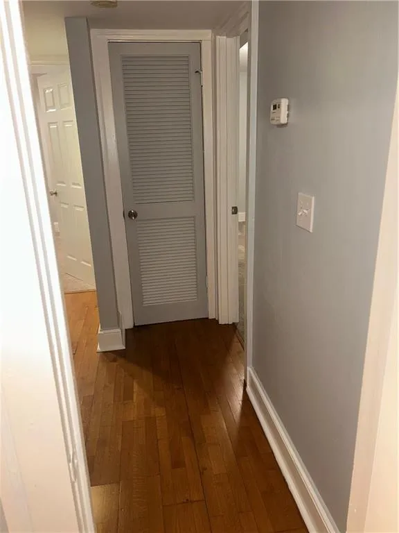 Corridor featuring dark wood finished floors and baseboards