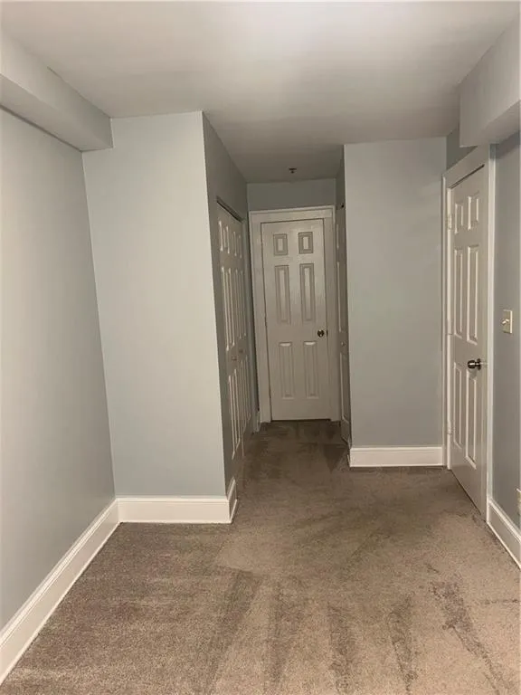 Corridor featuring carpet flooring and baseboards