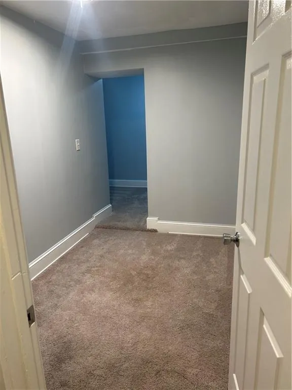 Carpeted spare room featuring baseboards