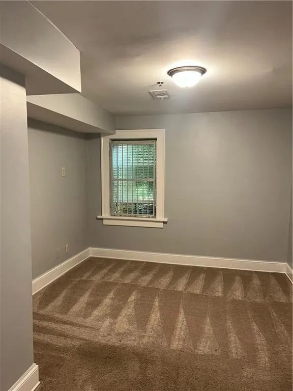 Spare room featuring dark carpet and baseboards