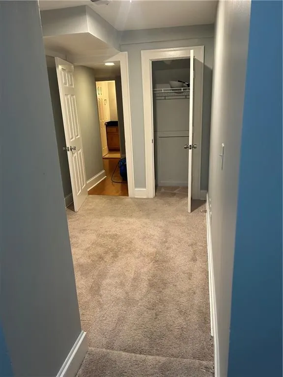 Hallway featuring carpet floors and baseboards