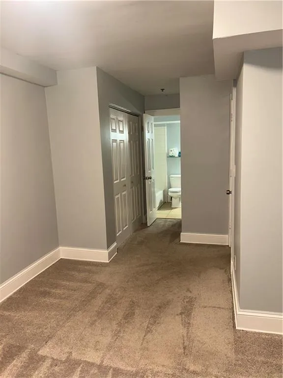 Corridor featuring carpet flooring and baseboards
