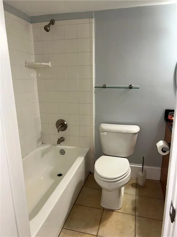 Full bath with toilet, tile patterned flooring, bathing tub / shower combination, and baseboards