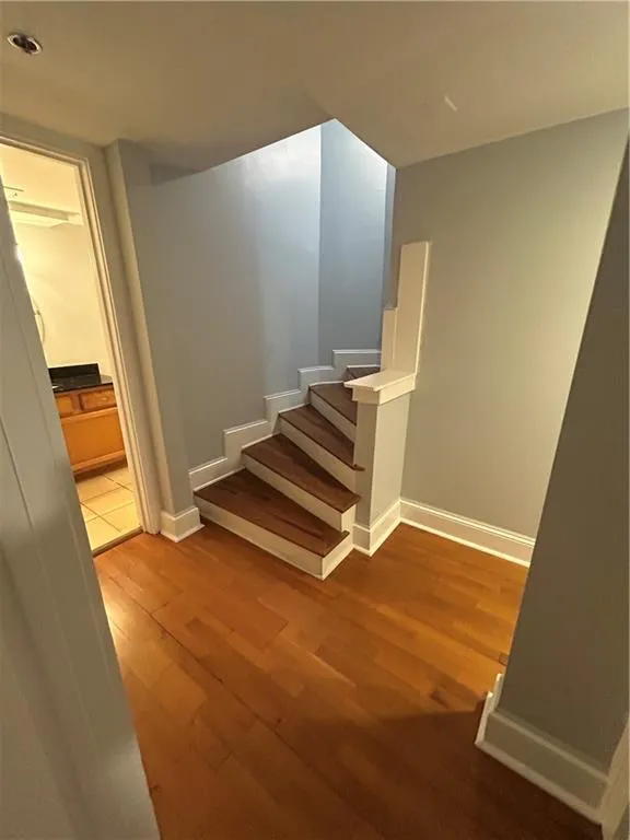 Stairway with wood finished floors and baseboards