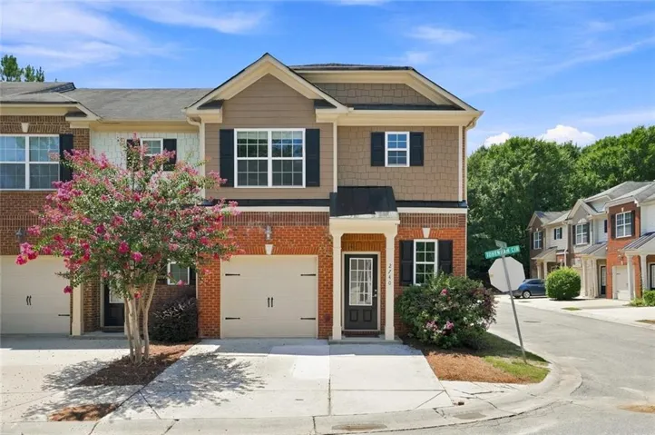 Two-story townhome featuring a brick and siding exterior with dark shutters