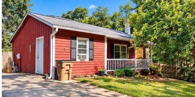 Red horizontal siding exterior with a white front porch railing, dark shutters, and a white chimney