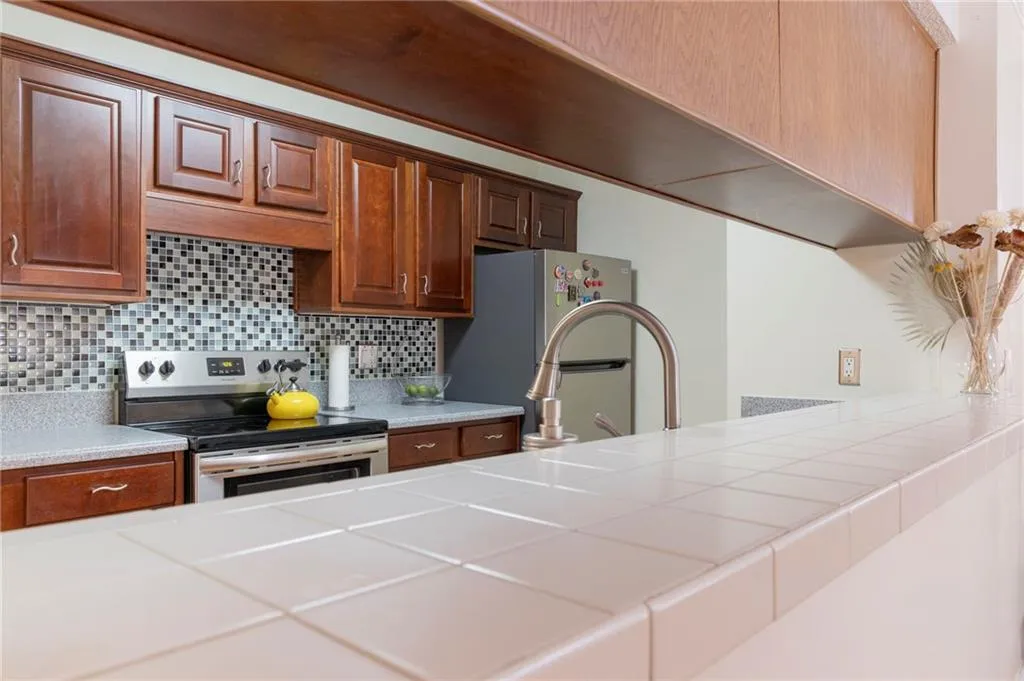 Kitchen with appliances with stainless steel finishes, tasteful backsplash, and tile counters