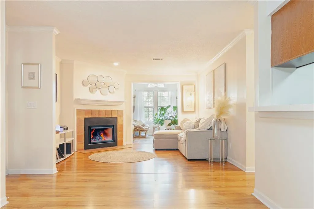 Living room featuring crown molding, a tiled fireplace, and light hardwood / wood-style flooring