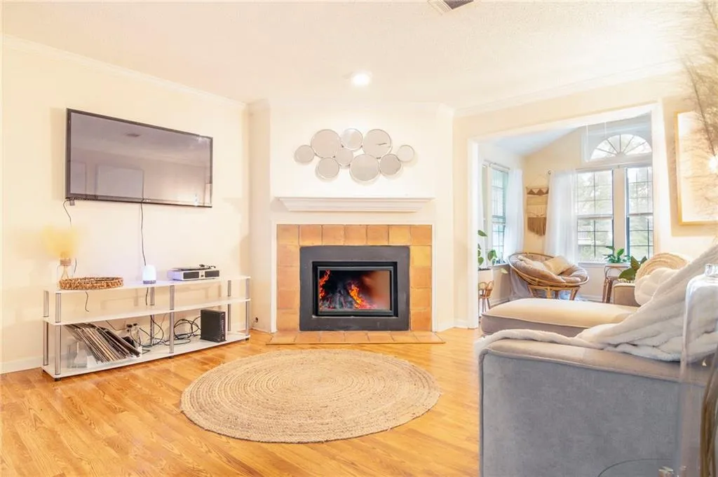 Living room with a tile fireplace, light hardwood / wood-style flooring, and ornamental molding