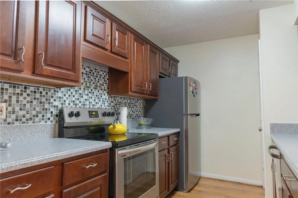 Kitchen with stainless steel appliances, light hardwood / wood-style floors, backsplash, and a textured ceiling
