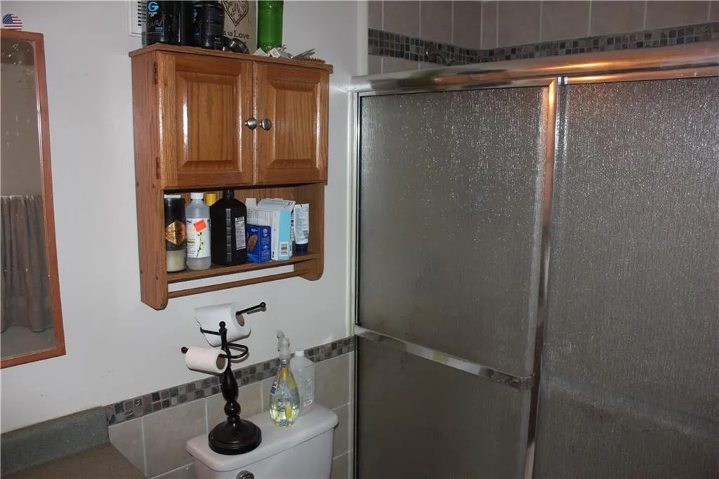 Full bathroom with a stall shower and tile walls