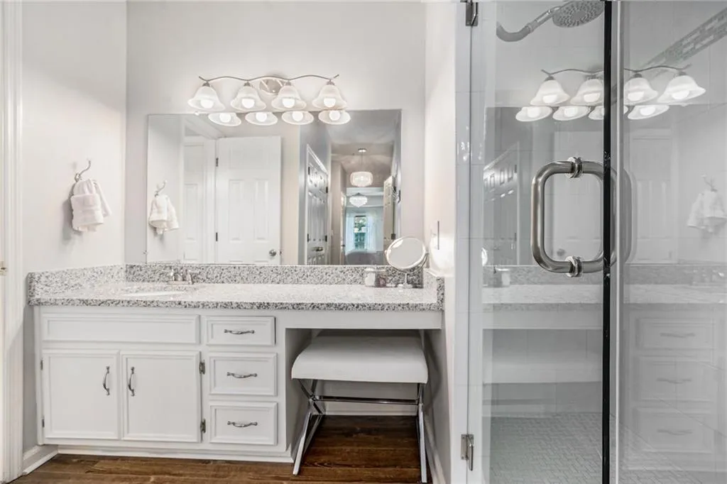 Full bath with vanity, a stall shower, and dark wood-style floors