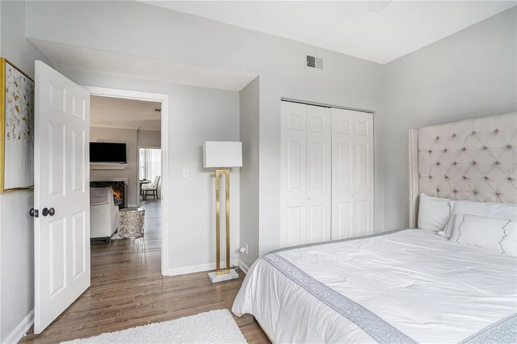 Bedroom featuring a lit fireplace, dark wood-style floors, a closet, and a ceiling fan