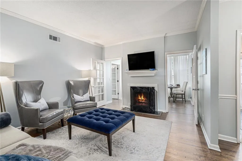 Living area featuring a warm lit fireplace, ornamental molding, and wood finished floors