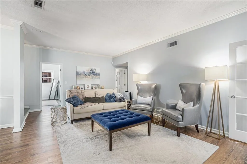 Living room with crown molding, a textured ceiling, and wood finished floors