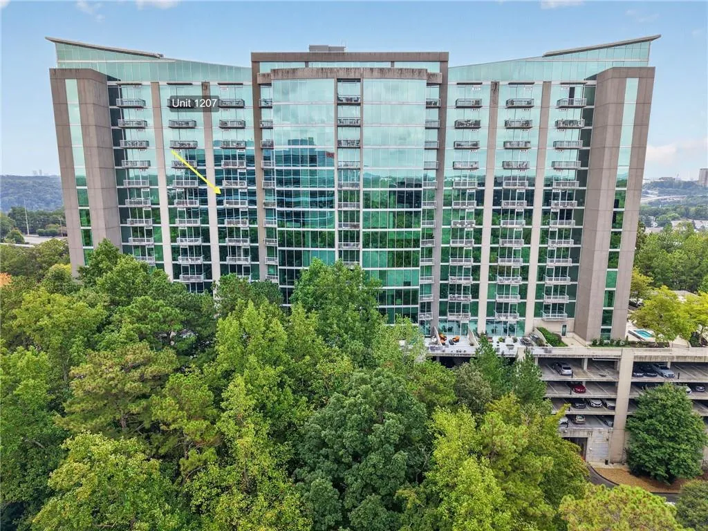 Modern high-rise building featuring extensive glass curtain walls, private balconies, and an integrated parking structure